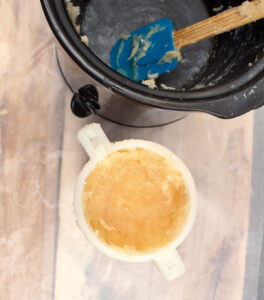 soap batter pressed in to a round mold with dirty spatula and slow cooker behind it